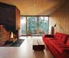 Modern home with Living Room, Sofa, and Standard Layout Fireplace. The interiors are clad in white-glazed pine, a contrast to the black-stained facade. The brick fireplace is original. Near a Polder sofa by Hella Jongerius for Vitra is a coffee table of Sævik’s design. The rocking chair is vintage and came with the house. Photo of Cozy Scandinavian Abodes