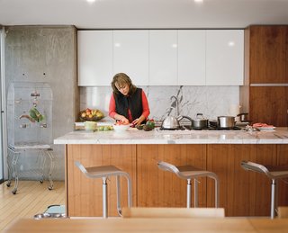 Angelica Becerril prepares food at the kitchen island; the Carrara marble countertop is one of the few luxury materials used in the house.