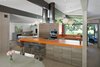 Modern home with Kitchen, Wall Oven, Range Hood, Cooktops, Pendant Lighting, and Undermount Sink. The architects went with a bold, orange hue for the kitchen countertops. Past the front door and a short hallway lies an expansive living, dining, and kitchen space. Photo of Renovated Midcentury Home in Austin Doubles Square Footage