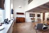 The shop is divided into two zones: a sales floor under a mezzanine and a tailering workshop dominated by machinery and storage racks. Photo by Dorota Zyguła-Siemieńska. Photo of A Polish Factory is Reborn as a Stylish Tailoring Studio modern home