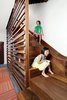 Modern home with Staircase, Wood Tread, and Wood Railing. The walnut staircase and slide in a Chicago town house leads from the main level to the basement. To protect people on the ride down, a “crash pad” fashioned from a standard gymnastic mat covers the wall at the slide’s base. Photo of Lakeview