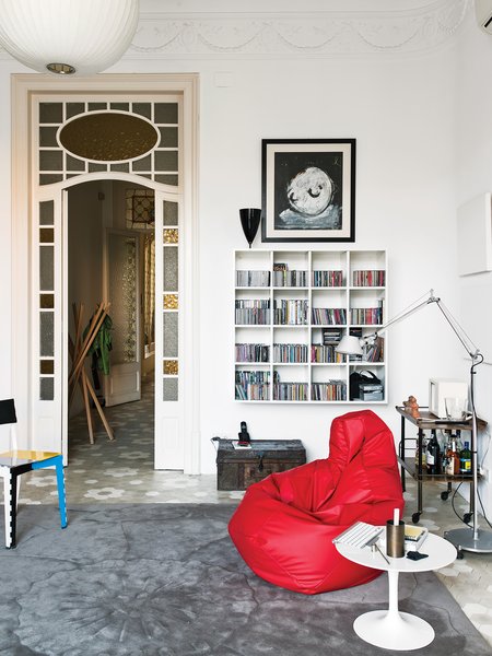 Vila D’Acosta-Calheiros hung a space-saving wall shelf in the library. The table is by Eero Saarinen; the Tolomeo lamp is by Michele de Lucchi for Artemide. The red beanbag-like Sacco chair is by Zanotta, as is the Sciangai coatrack in the hall, beyond.