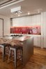 Modern home with Kitchen, White Cabinet, and Metal Counter. The island features a stainless steel countertop with a gas cooktop, oven, and a brick half wall. Photo of Clever Red Pegboard Backsplash in a Remodeled Kitchen
