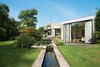Modern home with Grass, Trees, Back Yard, Exterior, House Building Type, and Concrete Siding Material. When Belgian fashion retailer Nathalie Vandemoortele was seeking a new nest for her brood, she stumbled upon a fortresslike house in the countryside designed in 1972 by a pair of Ghent architects, Johan Raman and Fritz Schaffrath. While the Brutalist concrete architecture and petite but lush gardens suited her tastes to a tee, the interiors needed a few updates. Photo of Water Features We Love