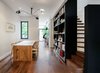 Modern home with Dining Room, Table, Ceiling Lighting, Chair, and Medium Hardwood Floor. The architects created the illusion of more space by opening up the floor plan, repositioning the staircase and introducing sight lines to the large windows on the south side. Recurring black accents—from the dining room’s Serge Mouille light fixture to its tall bookcases—contrast the brightness of the crisp white walls. Walnut floors and lighter wood furniture like the Klaus Willhelm table and Hans Wegner Wishbone chairs cozy up the home, while colorful objects animate it. “We strongly believe that people do not need more space, they just need better-designed space,” Dubbeldam says. Photo 2 of Contrast House