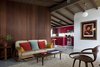 Modern home with Living Room, Sofa, Chair, and Rug Floor. The existing partitions were tongue-and-groove redwood. To update the interior, each panel was painstakingly removed, refinished in a darker hue, and replaced. The centerpiece, a four-strand rattan couch, is complimented by other wooden pieces, like this original Cherner chair, also a Craigslist purchase. Photo 5 of Hillside House No. 3
