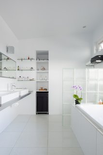 The bathroom’s glass block partition is just one example of the extensive list of repurposed materials used for this project. The sinks are from IKEA and bathtub is from Home Depot.