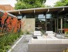 Modern home with Exterior, Mid-Century Building Type, and Shed RoofLine. Behind the resin screen is the property’s centerpiece: an entry garden that Trainor recast as an outdoor living room. Sparta stacking chairs, a deep-wicker Baia sofa, and matching Baia armchairs, all by Mamagreen, are arranged around a custom concrete fire pit. Orange kangaroo paws lean in from the sides, creating a sense of privacy without sacrificing views. It’s a welcoming space that serves as a casual gathering spot when the weather cooperates. Photo of Modern Master: Joseph Eichler