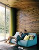 Modern home with Living Room, Sofa, Light Hardwood Floor, and Brick Floor. In the warm interior of the X House in Hennepin, Illinois, Diane Pascal and Thomas Richie enjoy the view from their boiled-wool Ligne Roset couch in the main living area, where wood paneling on the ceiling and walls mirrors the topography of the landscape. A gauzy green curtain adds a moment of color to the scheme. Photo 2 of New Grass Roots