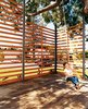 Gabriella swings on the rope swing hung from the podocarpus tree. The twenty-foot-tall, steel-framed, custom-built wood screen provides enough privacy to give the outdoor space the feeling of a room, with the 50-year-old polocarpus tree acting as a roof. Photo of Design Guide: San Diego modern home
