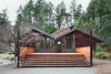 The architects added an extended deck that creates an opportunity for gatherings. It also smoothly transitions the interior level, which hovers above the ground on pylons, back to the earth. Steel columns were specially implemented so the clients could string lights over the deck. A fire-pit is now located in front of these steps. Photo 10 of Zema Redux modern home