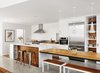 Modern home with Kitchen, Pendant Lighting, Marble Counter, Wood Cabinet, White Cabinet, Wall Oven, Range Hood, Refrigerator, Concrete Floor, Open Cabinet, Undermount Sink, Recessed Lighting, Range, and Subway Tile Backsplashe. Alter integrated wood from the original bungalow into the kitchen and covered the island in Carrara marble. New appliances include a Wolf range, a Broan hood, and a Miele oven and refrigerator. The Fucsia pendant lights are by Achille Castiglioni for Flos, and the benches are from RAD Furniture. Photo of Airy Kitchen Additions