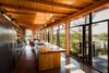 The home maintains remarkable material consistency, with Douglas fir cladding the beams, kitchen countertop, and interior walls. The open-plan kitchen absorbs views of the lake through an expansive glass wall. Photo of Kitchens with Killer Views modern home