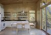 This neutral palette of the kitchen and living room allows the balcony’s vista to take center stage. Photo of Simple Cabin Embraces Its Mountain Setting modern home