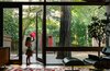 Modern home with Wood, Picture Window Type, Living Room, Recliner, Ottomans, Media Cabinet, Dark Hardwood Floor, and Rug Floor. With four children under the age of six, the Ruells have learned not to be overprotective of their collection of contemporary and vintage furniture. In the living room, an Eames lounge chair and ottoman sit on a Moroccan rug from M.Montague, while the family’s eldest child, Mirene, surveys the indoor/outdoor view. Throughout the house, Kolbe windows and fixed glass (in existing jambs) were added to increase energy efficiency. Photo of 47+ Midcentury Modern Homes Across America