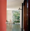 Modern home with Office, Concrete Floor, Study Room Type, Desk, and Chair. Van Everbroeck’s home office occupies the end of one arm of the building. An industrial outdoor light fixture is mounted on a black-painted steel post. The orange of the back wall was chosen to work with the glowing rays of the sunset and the silhouetted, dancing shadows of leaves. Photo of 17 Stellar Uses of Color in Home Offices