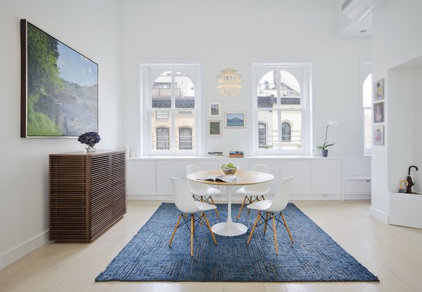 In a renovated Tribeca loft, Eames shell chairs surround a Saarinen Tulip table from Knoll. The Line console is from Design Within Reach and the pendant light is Louis Poulsen's Snowball. While architect Matthew Miller of New York firm StudioLAB gutted the space, some of the original details—like the windows—remain. The rug is from ABC Home.