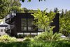 Modern home with Exterior, House Building Type, and Metal Siding Material. The decidedly industrial exterior features smooth dark gray stucco, a custom steel mesh wall, and a metal spiral staircase leading from the ground floor to the roof deck. The clients love the industrial look because it feels raw and natural to them. The footprint of the new addition lies at the rear of the existing home, and the dark exterior helps seamlessly integrate the new structure into the natural slope of the land. According to architect John Klopf, the new addition acts as a spatial backdrop for the existing structure, “receding visually out of respect for the original home.” Photo of This Modern Addition in Northern California Has the Ultimate Rooftop Hangout