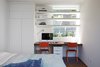 The guest bedroom also doubles as the primary homework area for the kids. Orange school chairs add a playful pop of color to the space. Large window openings bring in light and offer views of the lush surroundings. Photo of This Modern Addition in Northern California Has the Ultimate Rooftop Hangout modern home