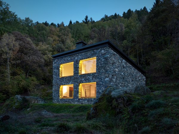 The positioning of the home’s roof allowed for a double-height, north-facing wall with four matching windows and an accompanying skylight. “The house refers to rural houses: a sloping roof, completely coated by stone and with no eaves,” Vanotti says.