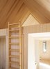 Modern home with Staircase and Wood Tread. The auxiliary cabins contain the sleeping quarters. A ladder leads to a sleeping loft underneath a gabled ceiling. The cabin’s bathroom is situated beneath the loft and features clean white fittings and tile. Photo of This Cozy Retreat Holds the Cure for Cabin Fever