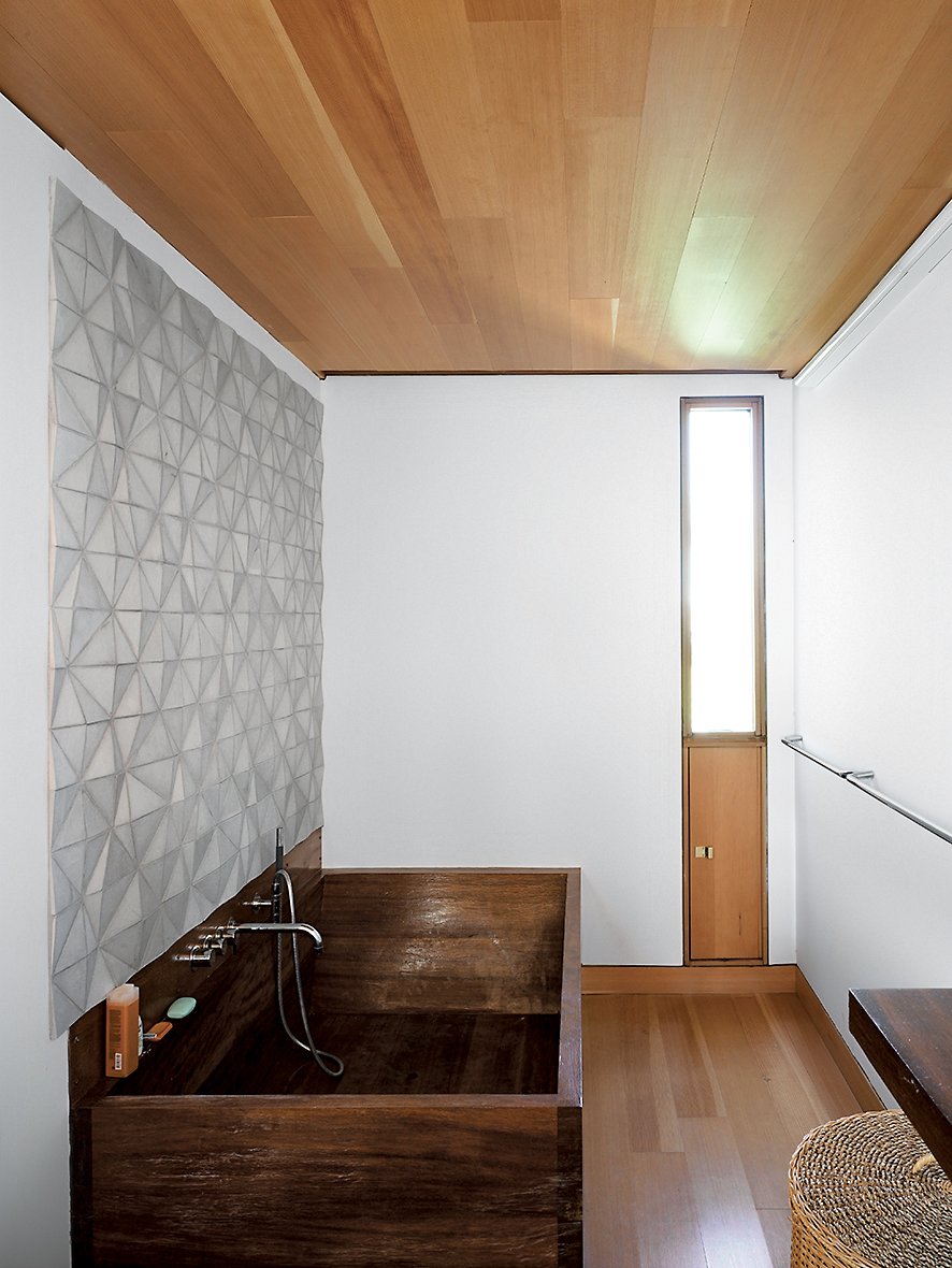 In the bathroom, a custom ceramic backsplash designed by Meredith and Sample joins an iroko-wood tub created by their students a the University of Toronto.