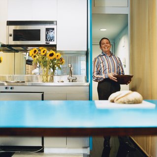 When slid toward the kitchen on custom tracks, the fold-down table gives Hughston much-needed counter space. Luckily, the apartment came with stainless steel appliances; Sanders covered the cabinets with matching Formica. A mirror behind the kitchen sink also adds a feeling of space.