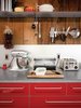 Modern home with Kitchen, Concrete Counter, and Colorful Cabinet. Harry Bates designed this simple cedar house for a young family in New York in 1967. Forty years later he updated the place for its new owners, Joe Dolce and Jonathan Burnham. The addition of bright red cabinetry in the kitchen introduces a contemporary style without losing the rustic, vintage quality of the space. Read the full article here. Photo of Space-Saving Hacks for Small Kitchens