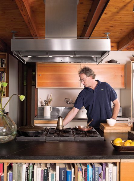 A pair of environmentally attuned architects combined adjoining properties in a Los Angeles canyon to house their modernist menagerie. With exposed industrial materials for finishes, the interior includes hand-troweled, waxed concrete floors, Douglas fir beams, and sealed-plywood ceilings. The open kitchen’s island, topped with soapstone, doubles as a bookcase for the living room.