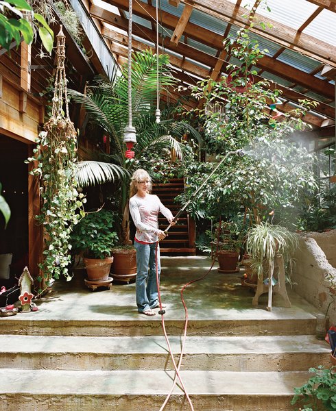 Sue waters the indoor foliage with an industrial hose hung from the ceiling.
