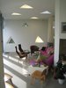 Modern home with Living Room, Rug Floor, Chair, Sectional, End Tables, Wall Lighting, and Ceiling Lighting. Here you can see the triangle motif from the exterior moved inside into the living room style space. Though many of the triangles are in fact windows punched into the envelope of the building, many others are actually lights. There's plenty of natural daylight from the massive glazed window on to the terrace, though. Photo of Maggie's Center by Zaha Hadid