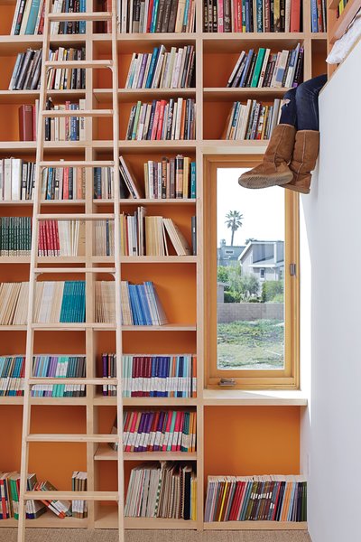 To make the most of 13-foot-high ceilings that help draw hot air out through second-floor windows and doors, designer Daniel Garness painted select walls with playful color and lined them with maple plywood bookcases. Library ladders (about $1,500 each from Alaco Ladder Company) provide access to reading material and a sleeping loft.
