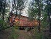 A screen porch runs the entire length of building, built over a dry creek bed on embedded concrete piers. The architect says he worked with the varying topography and native pines, turning the building 30 degrees at one point to accommodate the natural contours of the land. Photo of Texas Bunkhouse modern home