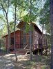 A stone path leads from a gravel parking area to the entrance, fronted by a wide stair and small porch. “Since we had to slot it in between so many trees with such vertical proportions, we decided our building would have vertical proportions,” says Panton. At left is the enclosed bunkroom, with the double-height screen porch at right. Photo 2 of Texas Bunkhouse modern home