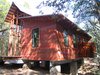 The structure was built onto a concrete-and-steel base. At left is the porch, pre-screening; at right is a cantilevered outdoor shower off the bathroom. The exterior cladding is cedar, stained in four different colors then placed randomly “for a different palette of colors, like a blend of bricks,” says Panton. “The owner’s favorite color is purple, so we added a purple board here and there.” Photo 4 of Texas Bunkhouse modern home