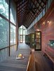 A view back toward the entrance. The purlin ceiling beneath the porch’s gabled Galvalum roof is made up of two-by-four cedar strips. A frieze of screened openings runs the length of the building, allowing a cross-breeze and extra light in, while ceiling fans keep the air circulating in summer. “Animals, from deer to raccoons to all kinds of birds, come right up to the porch,” says Panton. Photo 10 of Texas Bunkhouse modern home