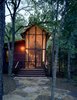 The architectural relationship between the bunkroom and porch, and the bunkhouse and the surrounding forest, is especially apparent at dusk, when the building reads as a kind of illuminated lantern. Photo 13 of Texas Bunkhouse modern home