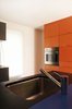 Modern home with Kitchen and Colorful Cabinet. Bright orange and cobalt-blue surfaces dominate the minimalist kitchen. Photo of Canada's Design Domestic