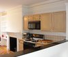 Chris removed the existing cabinets, microwave, oven, and stove from the cutout in the kitchen and filled it in with Ikea cabinets to create a flush wall that runs nearly the entire length of the public space. Photo of D House Kitchen Renovation modern home
