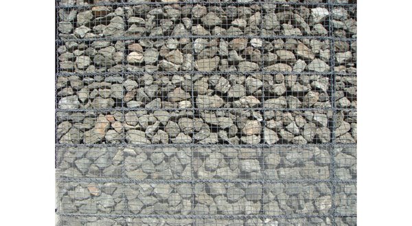 The exterior walls of the structure are industrial wire cages filled with locally sourced basalt.