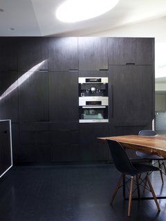 A wall of built-ins in the kitchen houses a raft of Miele appliances including a refrigerator, microwave, and espresso machine.