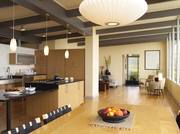 A view from the dining area. The architects arranged for the large original fireplace to be taken down to maximize space, and added a new dividing wall between the living room and the kitchen. The island, outfitted with a gas cooktop from Fisher, is new. Its surface extends to an adjacent workspace, beneath which is plenty of clearance for wheelchairs or stools.