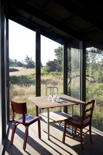 Dining Room, Light Hardwood Floor, Chair, and Table The screen porch serves as an auxiliary dining area and is furnished with a Teak outdoor table from Ikea surrounded by three chairs, including two vintage chairs and a silver 1006 Navy chair by Emeco from Design Within Reach.