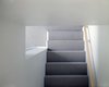 A commercial-grade gray carpet runs up the steps and throughout the second floor. Its short pile keeps the edge sharp on the stair treads, as well as being easy to maintain—a priority for the family, and one that guided many of their design decisions. Photo: Atelier Waechter. Photo 4 of Portland's Cape Cod Remodel modern home