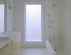 An IKEA vanity is suspended off the floor, making it easy to clean. The Spartan style and sense of space is enhanced here, as elsewhere in the home, by the oversized windows, white hues, and lack of architectural frippery or frills. Kohler shower fixtures complete the look. Photo: Atelier Waechter. Photo 6 of Portland's Cape Cod Remodel modern home