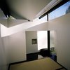 Modern home with Living Room and Rug Floor. Inside, a large window opposite the main door frames a view of mature trees. The main interior spaces is the raised platform supporting three tatami mats. "The floor of glossy ebonized birch has the sensation of a deep, still pond," Poss says. "The grass tatami mats become an island within an island." Photo by Phillip Kalantzis-Cope. Photo of Butterfly Roof Meditation Hut