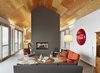 Though technically all one space, the living room, dining room, and kitchen are separated by the double-sided fireplace. When the couple comes to the house, the stay is center around relaxing, reading, walking, snowshoeing, and, in summer, swimming in the pool. Photo 4 of The Farm modern home