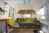 Here's the finished sofa bed. The sofa is upholstered in Designers Guild fabric. The curtains are from Ikea. The chair is from Cost Plus. And the wall cupboard above incorporates some of the trailer's original mahogany wood. Photo of Big Sur Airstream Renovation modern home