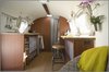 Here's the custom-built galley kitchen and bar. They installed new mahogany laminate to match the original furniture. Brandes designed the ceiling lights, and Area 63 fabricated and installed them. Photo of Big Sur Airstream Renovation modern home