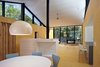 In the naturally lit central living space, stained plywood is used for the walls and flooring. The interior boasts high ceilings, a wood-burning fireplace, and a dining table by Robert Ewert Designs. Photo of Superior Logic modern home